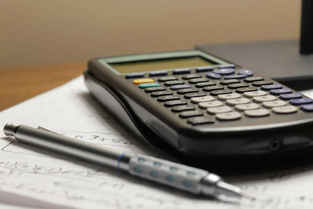 Calculadora y lápiz sobre una hoja con anotaciones