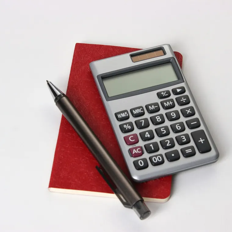 Calculadora y lápiz sobre una libreta roja para preparar un presupuesto