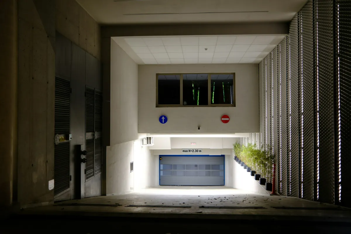Acceso al estacionamiento de un edificio con portón de garaje iluminado
