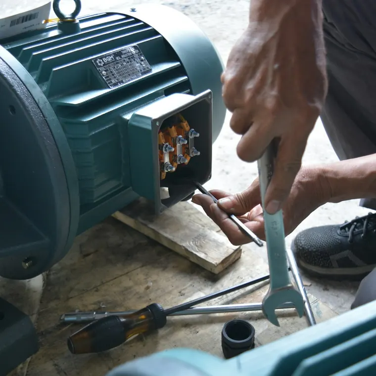 Técnico ajustando con una llave la caja de conexiones de un motor eléctrico