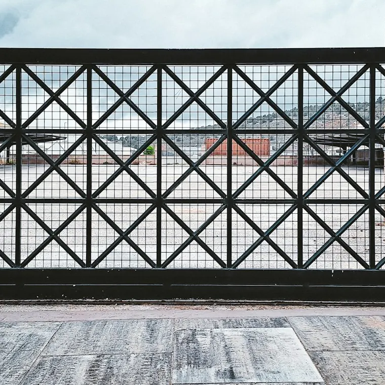 Portón corredizo metálico con diseño de rombos sobre su riel