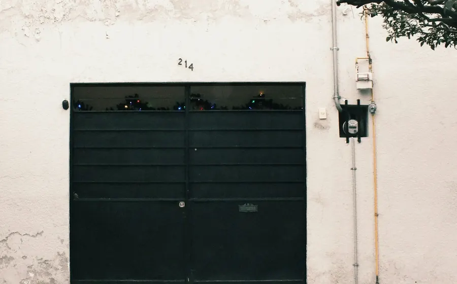 Portón de garaje negro en una fachada blanca